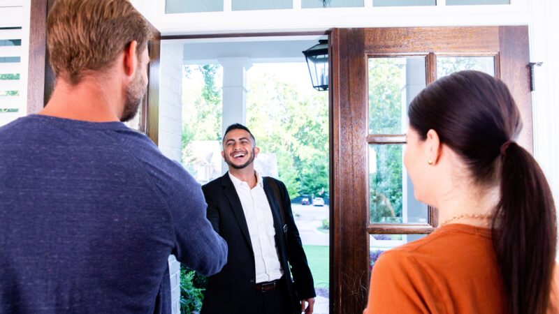 An agent in the doorway meeting his clients with a home with a lot of natural light